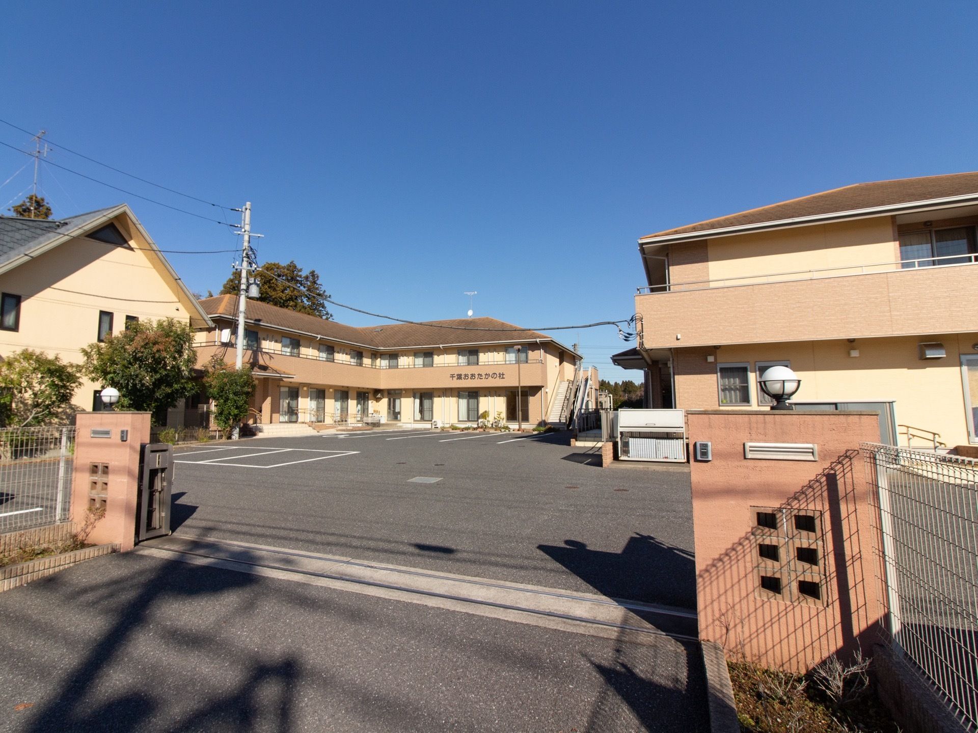 敷地入口に門のある、ブラウンを基調とした２階建ての建物である。十分な数の駐車場が敷地内に完備されている。