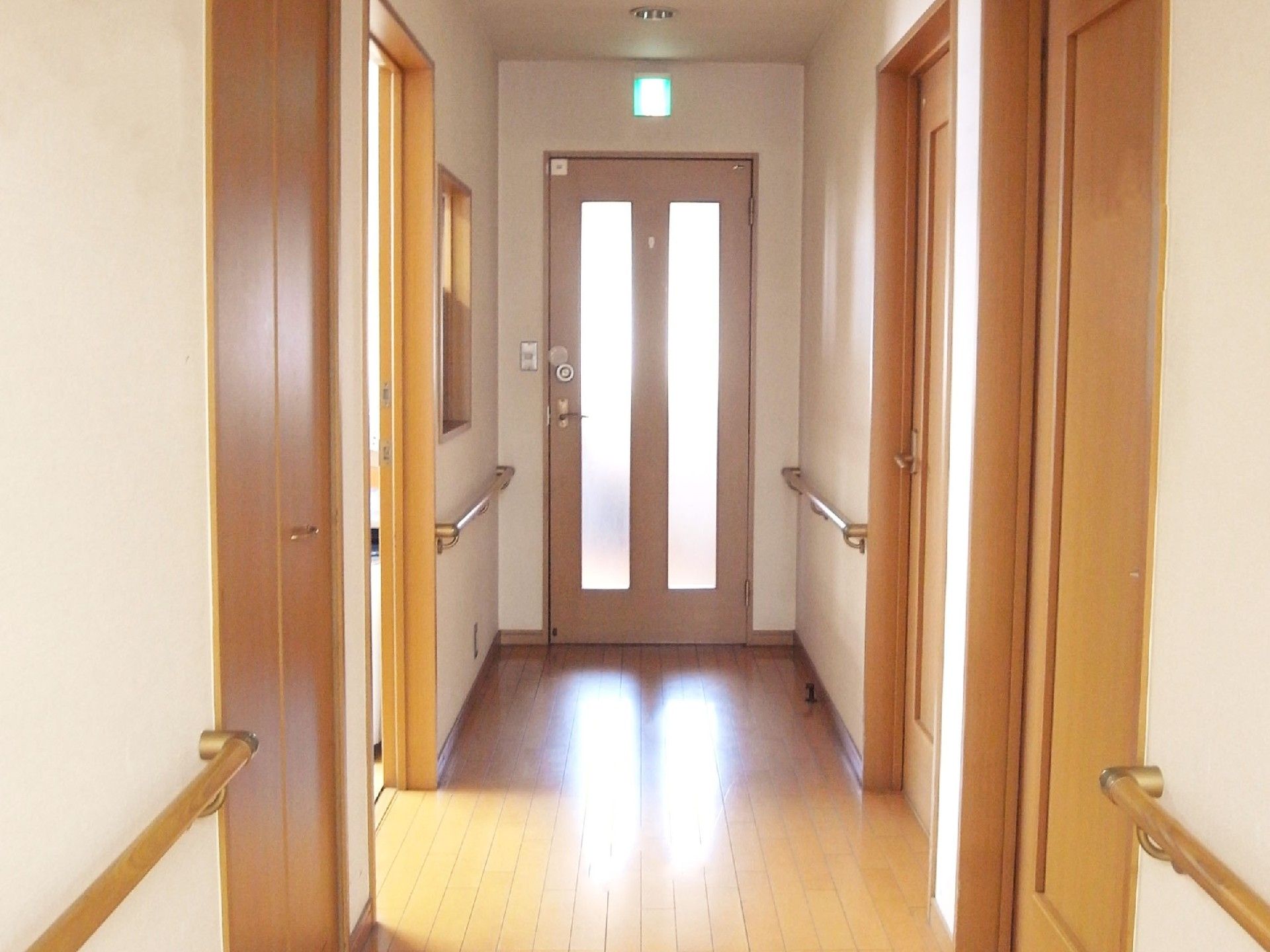 まっすぐな廊下の両サイドに手すりが付き、居室のドアは木製。