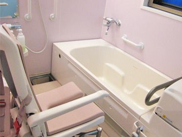 白とピンクの機械浴が置かれたタイル張りの浴室にはシャワーも付いている。重度の人も入浴できる設備。