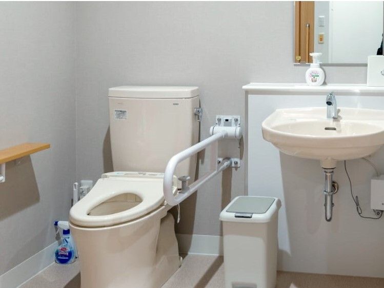 トイレの様子を写した写真。丈夫な手すりと洗面台がある広めのスペース
