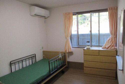 白い花の咲く道を散歩する車椅子に乗った高齢女性とヘルパー