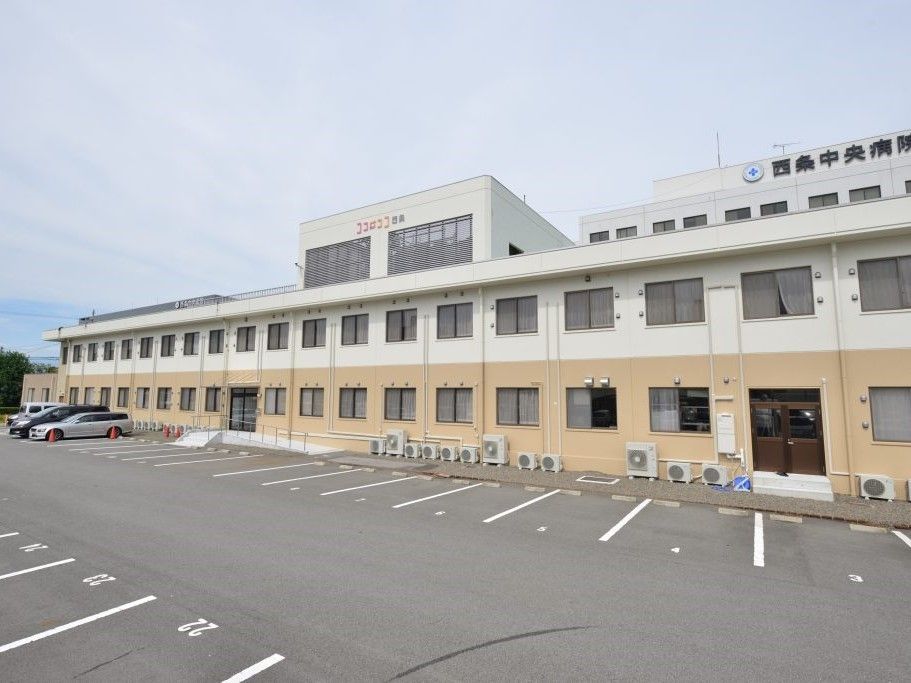 横に長い鉄骨造の建物写真。広めの駐車場スペースが広がっているのが分かる