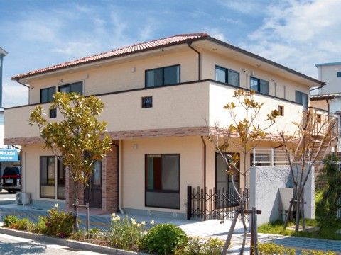 晴天の日にクリーム系の外壁に瓦屋根の２階建て施設外観