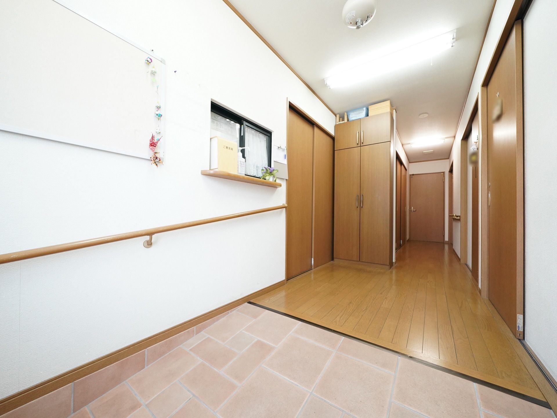 ブラウンで統一された廊下である。壁には手すりがついており、スロープにより段差を解消している。部屋の入口はスライドドアを採用している。