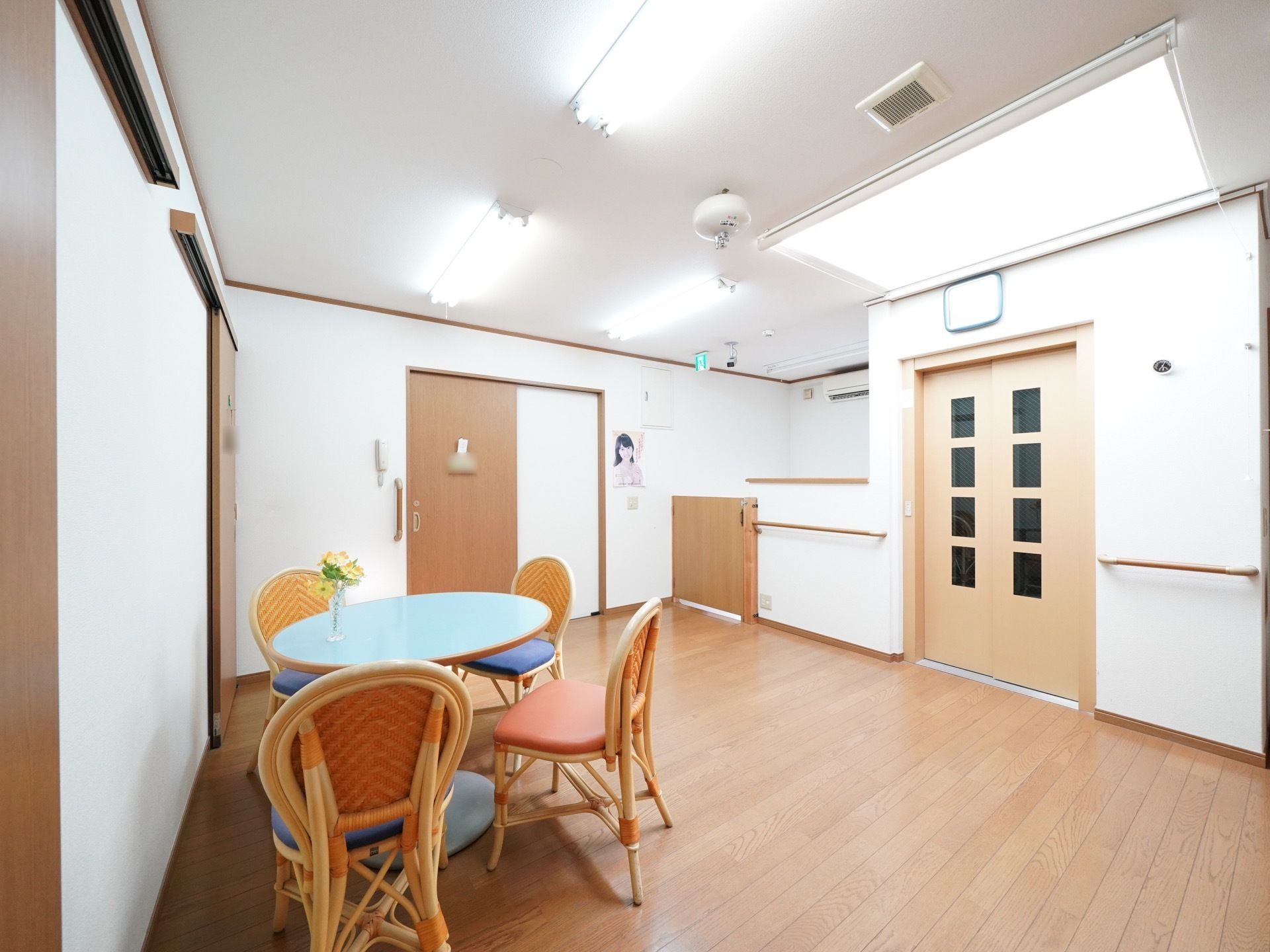 明るい談話室には、机と椅子が設置されており、壁には手すりが取りつけられている。各扉はすべてスライドドアを採用している。