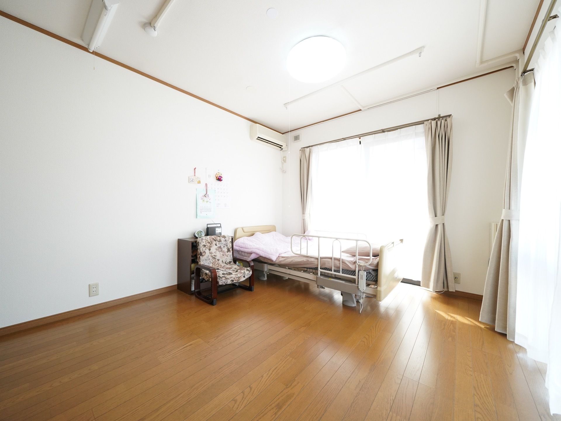 二面に窓のある居室で、とても陽当たりが良く広々としている。電動介護ベッドやエアコンなどの設備が整っている。