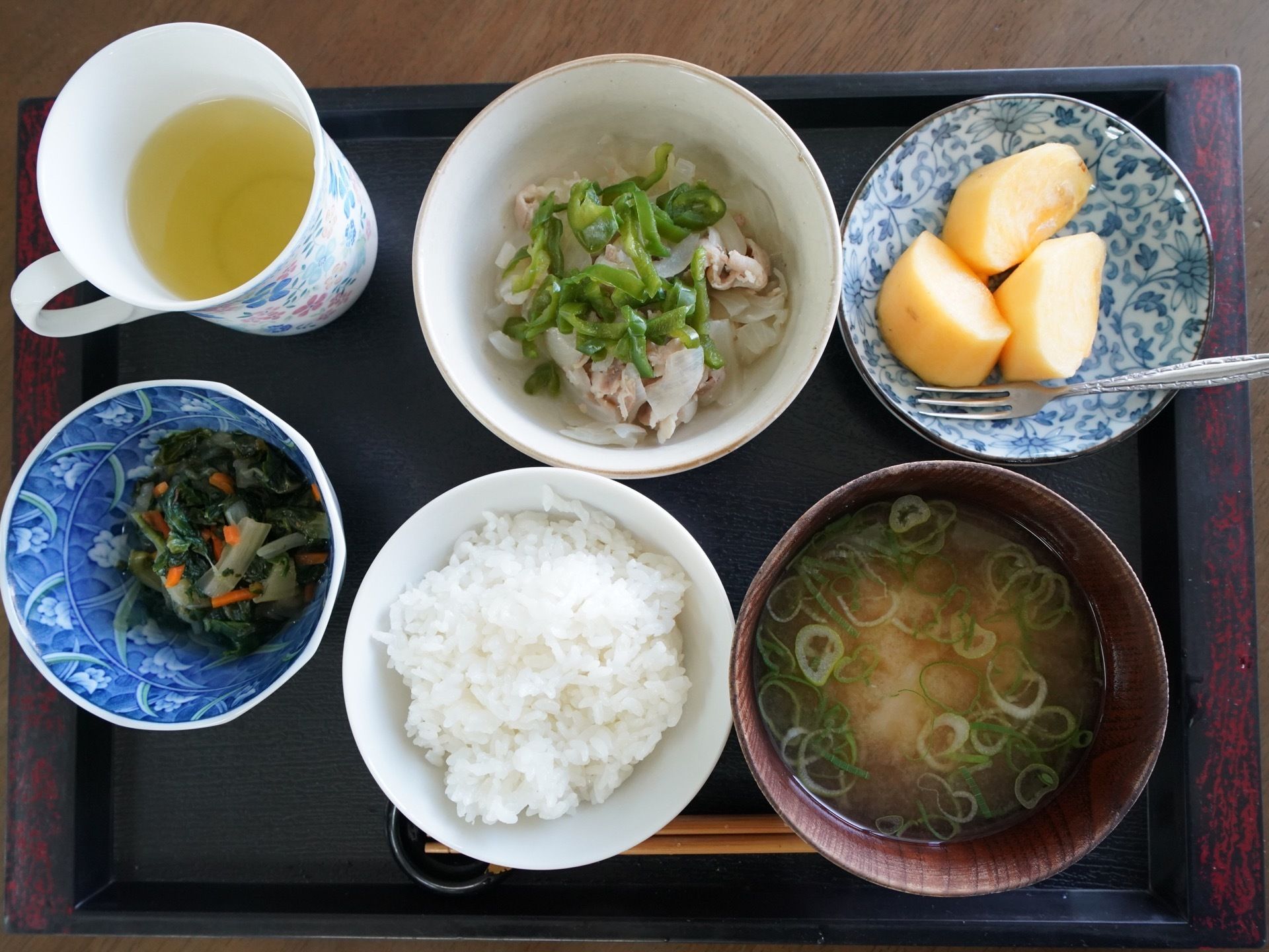 食事の一例である。主食の米飯、味噌汁と、主菜、副菜が１品ずつ、デザートの果物とお茶がお盆の上に並んでいる。