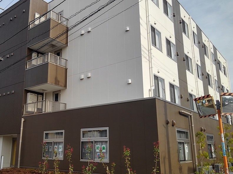 窓にエクラシア昭島と表示されている茶色と白の外壁の4階建て建築物