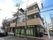 施設は交差点の角の部分に建っている。３階建ての建物でタイル張りである。建物の前に駐車スペースが用意されている。