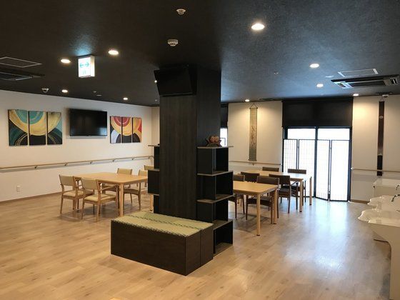 黒い壁や天井がおしゃれなカフェのような雰囲気。ダイニングテーブルが並び、畳のベンチや洗面所もある。