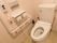 ストライプ柄の壁紙が張りめぐらされたすっきりとしたトイレスペース。手すりの上方に、ナースコールが取りつけられている。