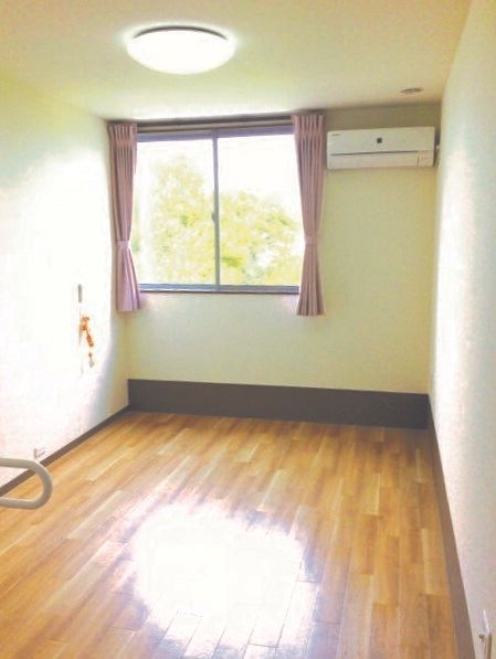 フローリングの部屋には大きな窓があり、窓にはレースカーテンとカーテンが付いていて外の景色が見える。エアコンも完備されている。