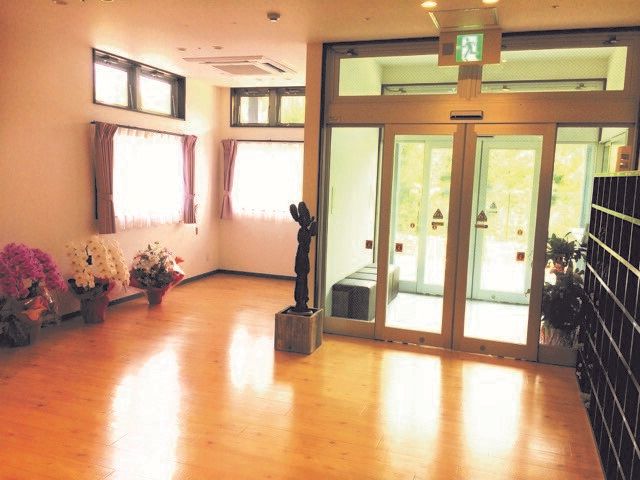 エントランスには風除室が設置され、大きな靴箱も置かれている。エントランスを入ってすぐの場所にお祝いの花が並び、窓にはカーテンが付いている。