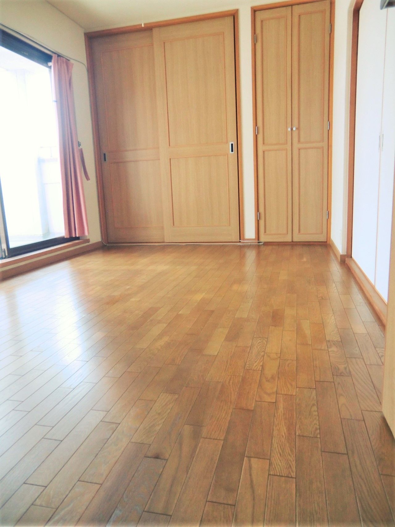 収納付きの広めの居室の様子。左側にベランダにつながる窓がある
