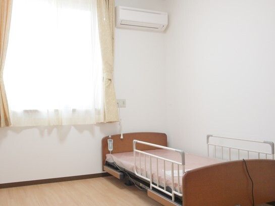 介護用ベッドが置いてある窓付きの居室の様子。施設内の部屋の写真