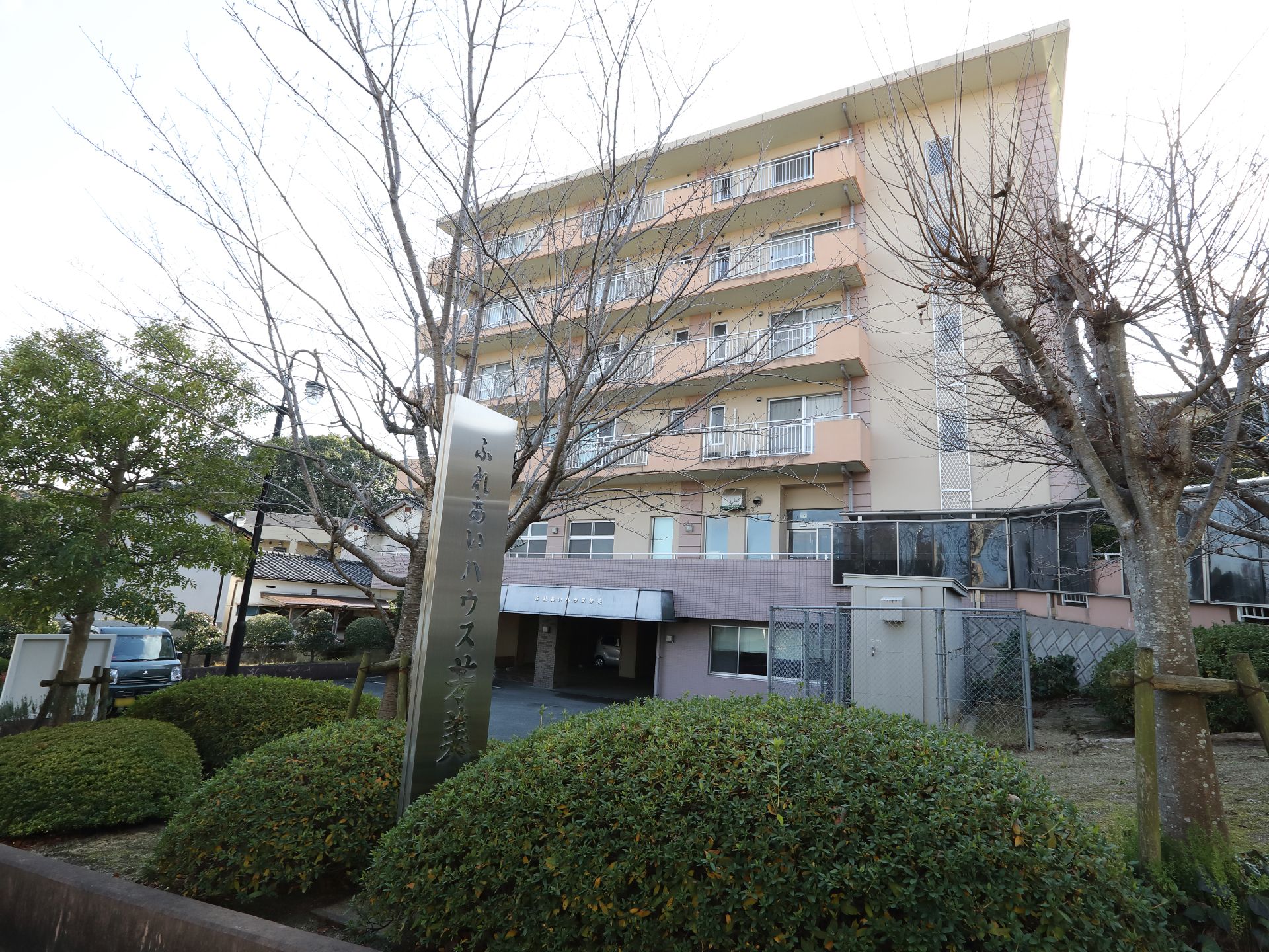 右側には屋根付きの通路があり、その先には６階建ての建物があり、敷地内には駐車場がある。