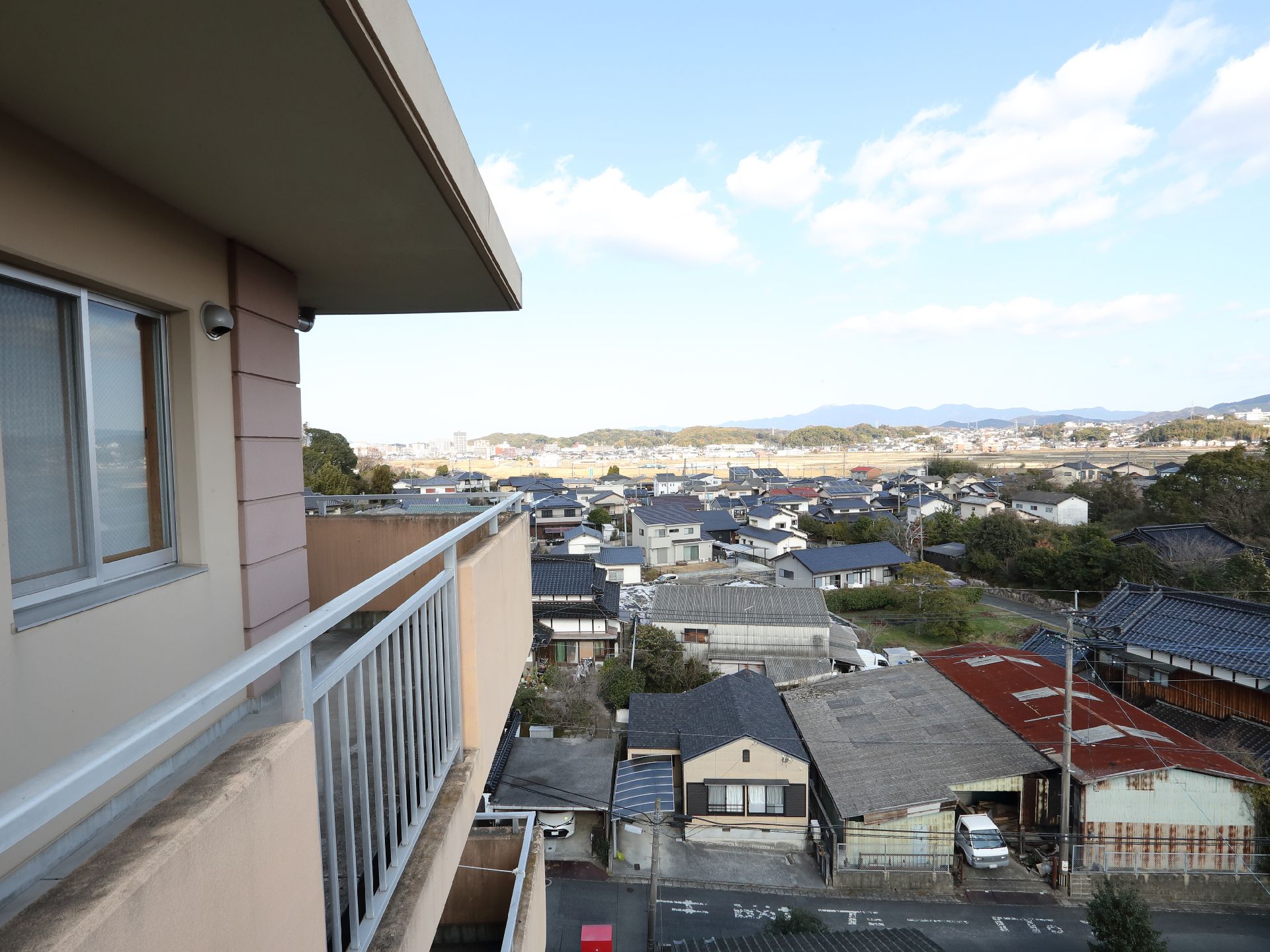 事業所名が書かれた屋根が付いている玄関の周りには駐車場があり、車が止まっている。