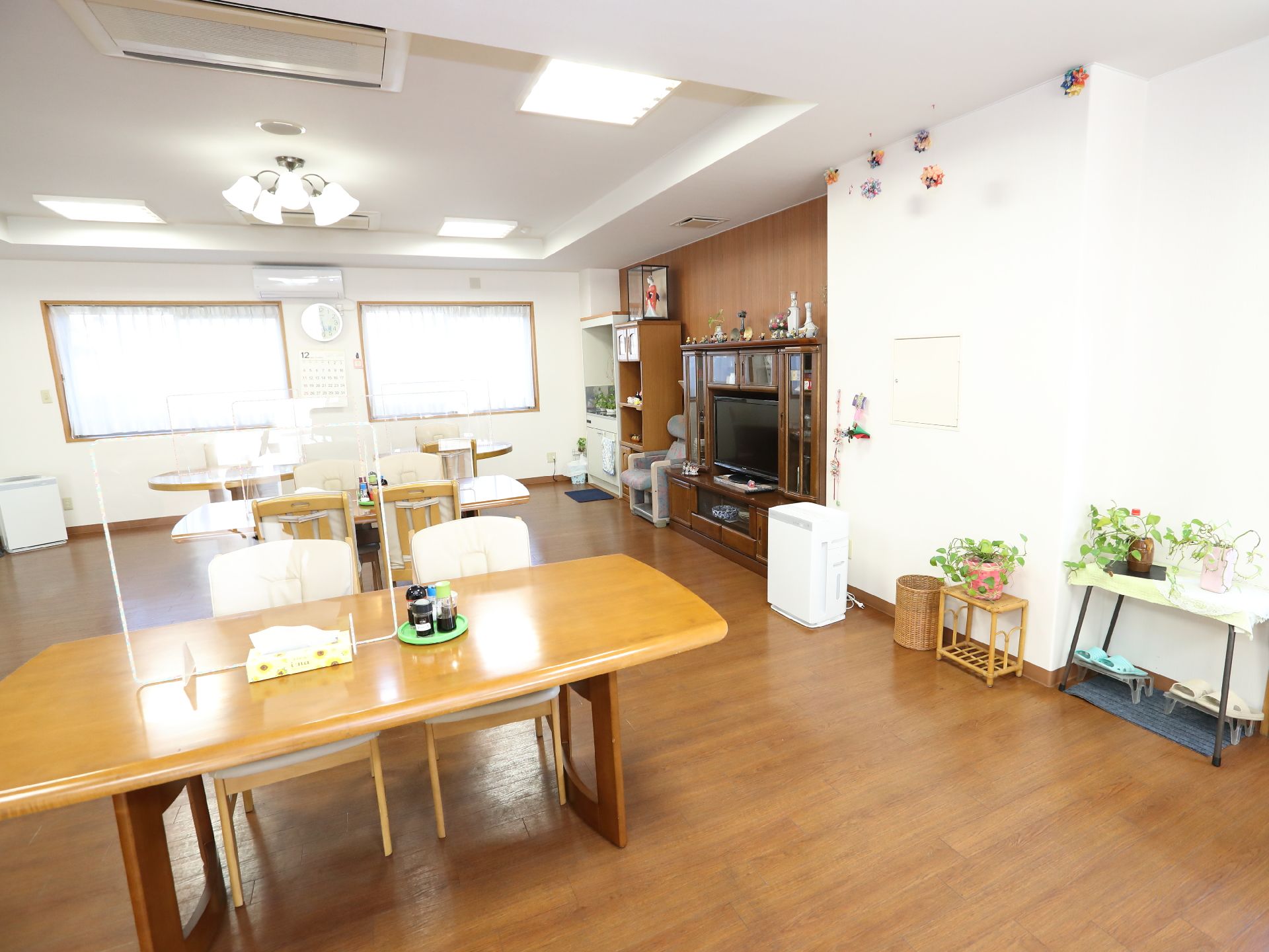 眼鏡をかけた高齢男性が笑顔でそばに立っている高齢女性と話している。