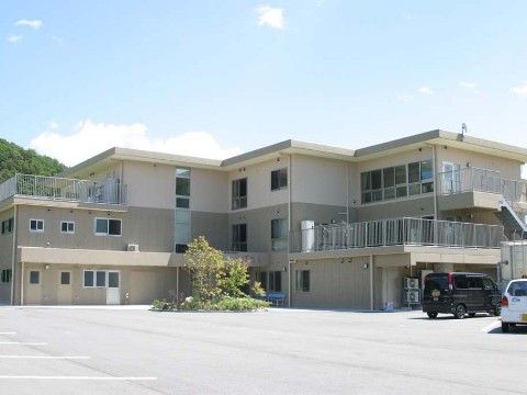 前面に広々とした駐車場を設けツートーンカラーの３階建て施設の外観