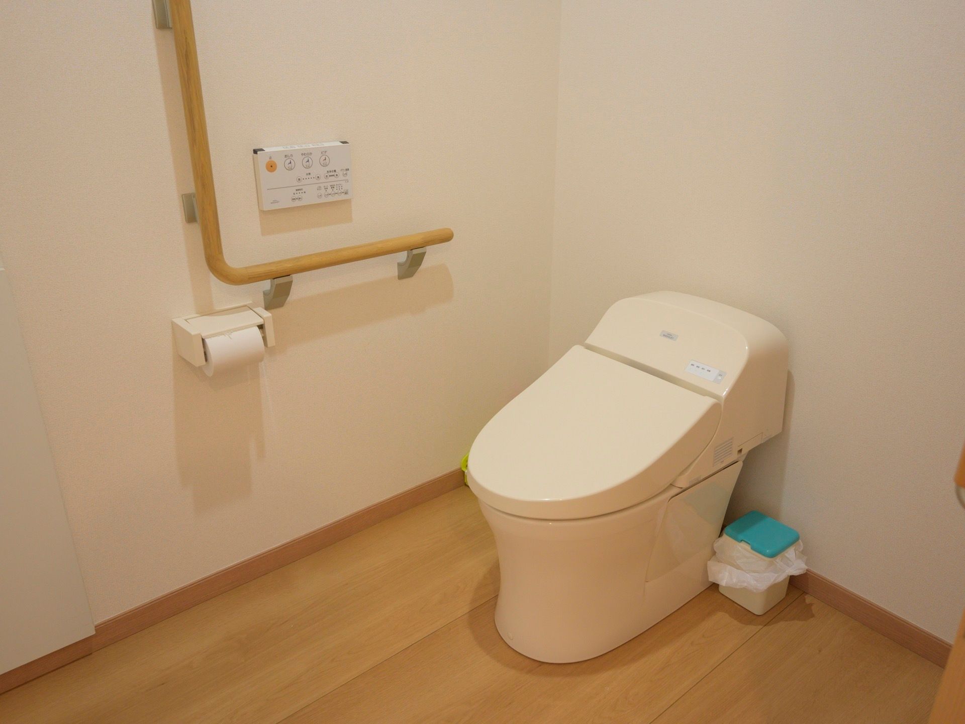 フローリングのトイレがある。壁にはＬ字型の手すりが設置され、車椅子のまま入れる広さが確保されている。