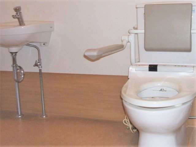 手すりが付いている介護士用のトイレ。ふたのないタイプが設置されている