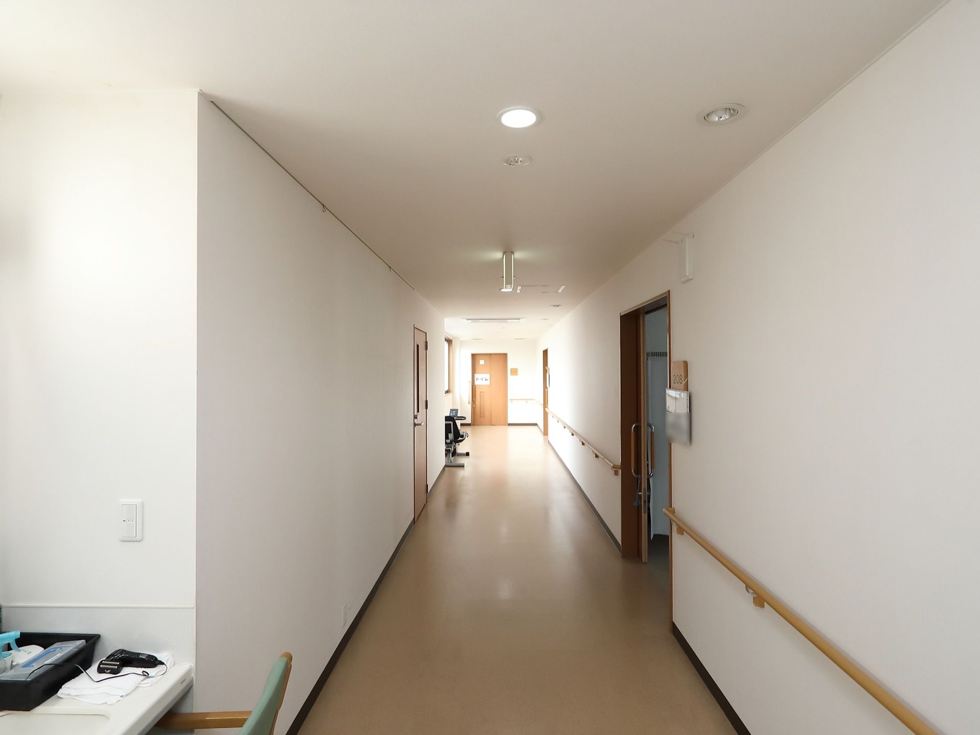 居室のドアが並ぶ廊下スペースである。掃除が行き届き、綺麗に整えられた空間である。片側の壁に手すりを設置している。