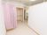 淡いピンク色のカーテンが、トイレ横のスペースとの仕切りとして吊り下げられている。天井付近には、壁掛け扇風機もある。