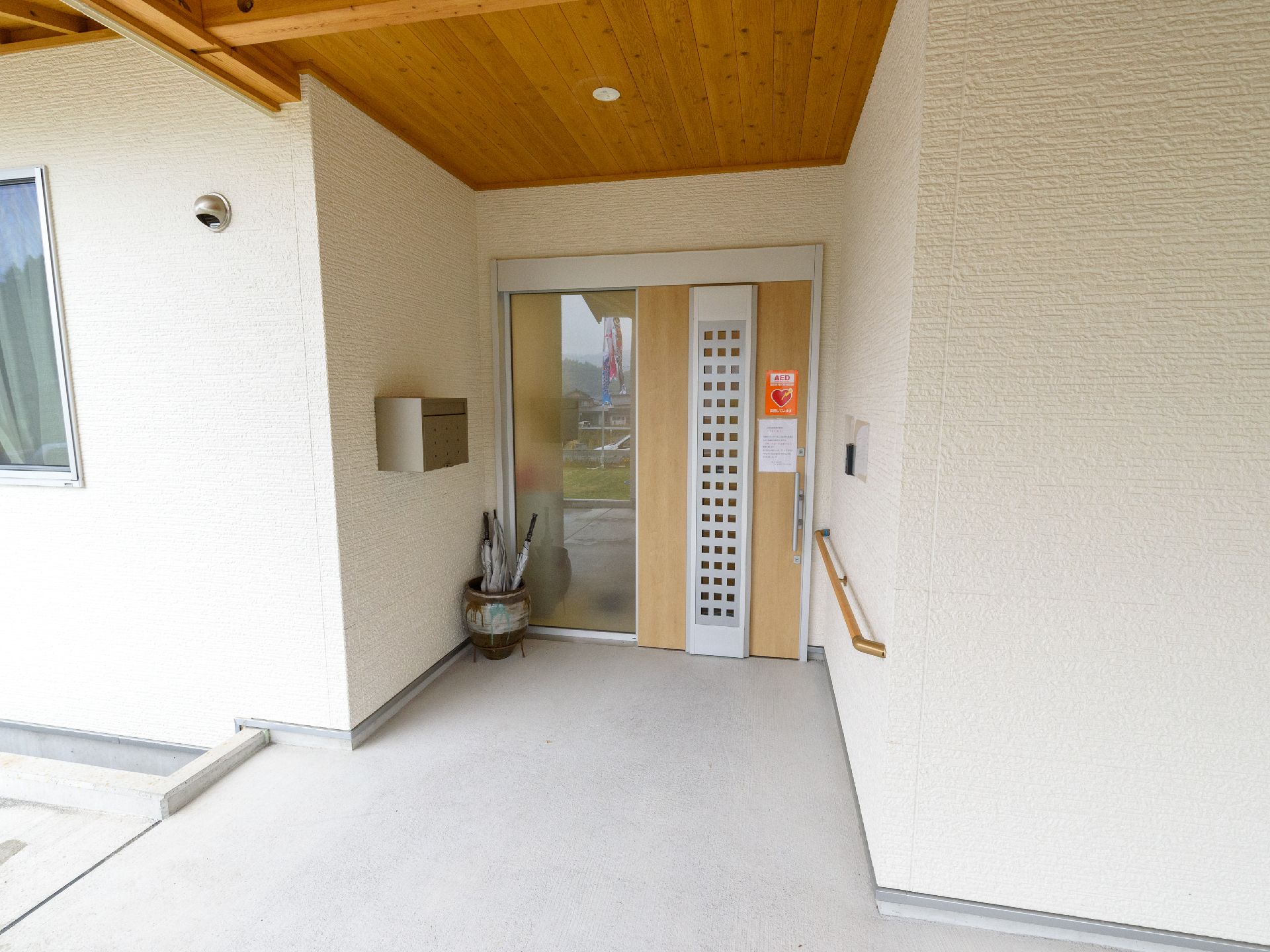 玄関扉の持ち手の位置まで壁面に手すりを設けた正面入口
