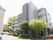地上５階建ての施設建物を外から見たところ。玄関は植え込みで囲まれており、裏手には駐車、駐輪用スペースを備えている。