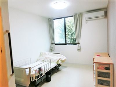 介護用ベッドとエアコン、タンスなどが置いてあるワンルームタイプの部屋の様子