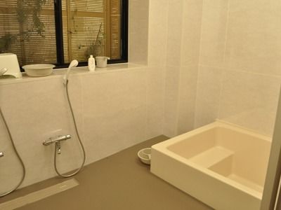家庭的なサイズの浴槽の様子。自動でお湯を張れる装置とシャワーチェアが置いてあるのが分かる