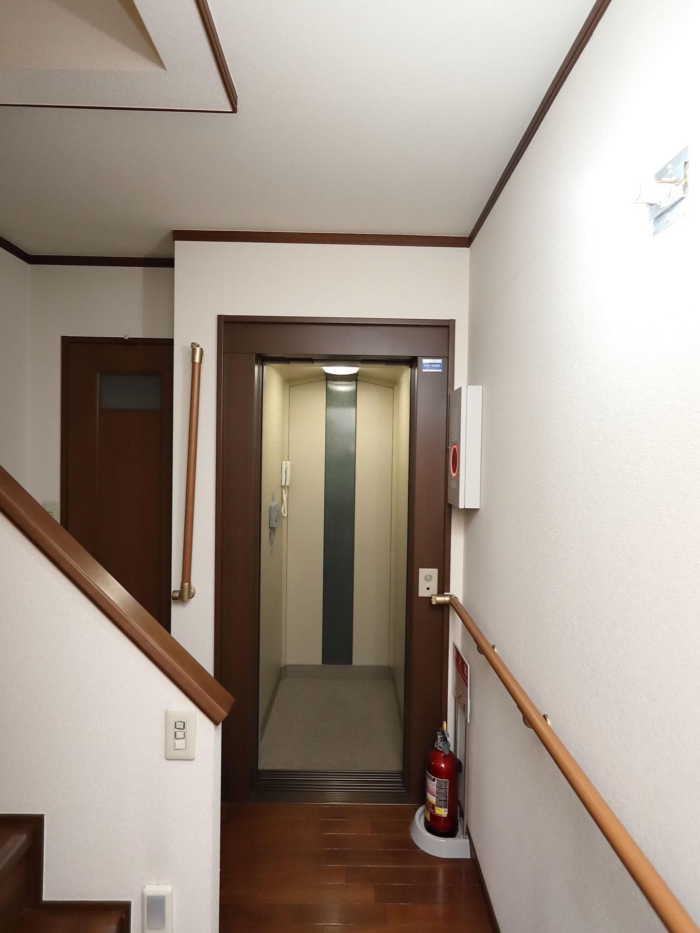 エレベーター内部の壁には、白色の施設内電話が設置されている。外の操作パネルにはボタンが１つだけついている。