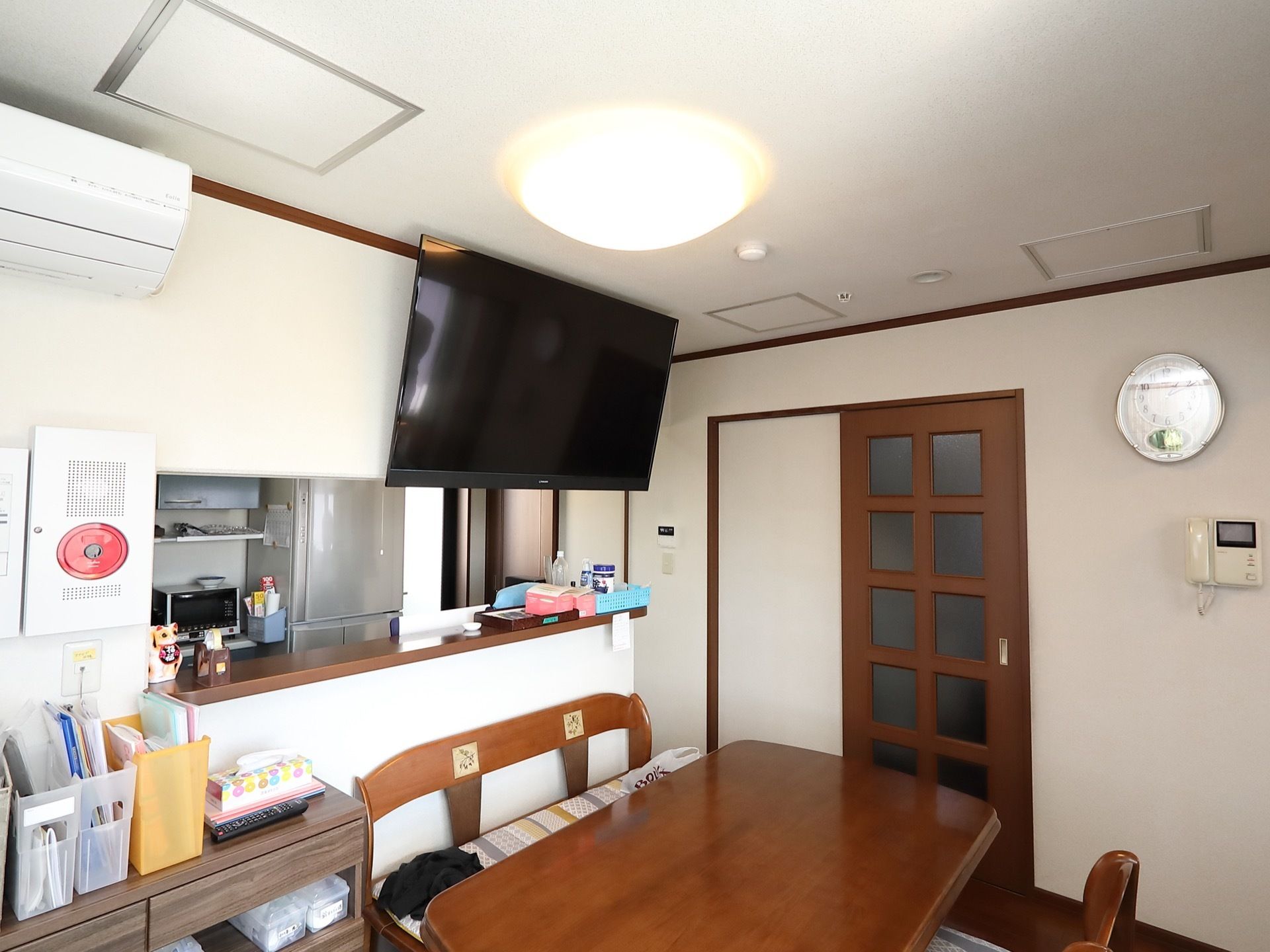 食堂にはテーブルが１つ置かれている。キッチンカウンターの上には壁掛け式の大画面テレビが設置されている。
