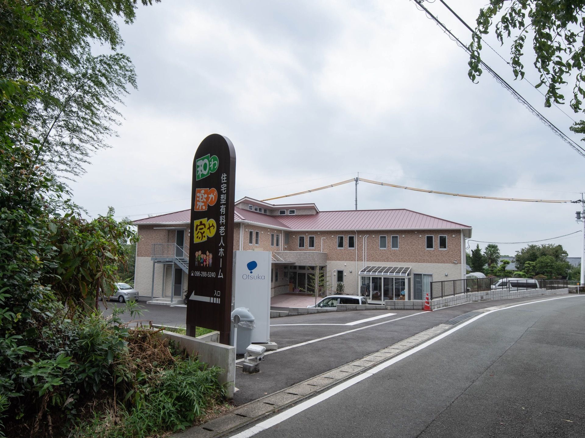 施設の敷地前には、道路から見やすい位置に金属製の看板がある。カラフルな文字で施設名が書かれている。