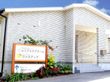 青い空の下にある白を基調とした平屋建てのホーム。看板も立っている。