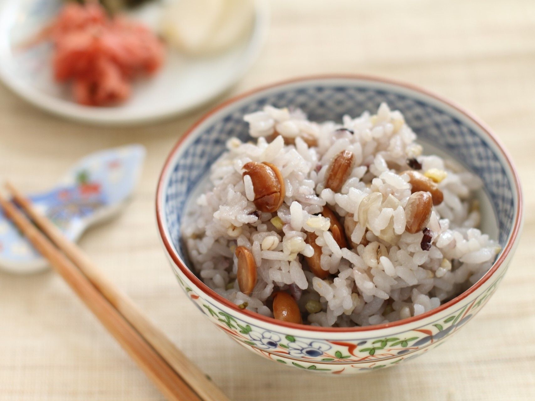 木製のテーブルの上には豆ごはんが置かれ、箸置きには木製の箸が置かれている。