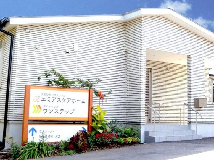 手すり付きの階段が付いた玄関の周りには草木が植えられ、看板も立っている。