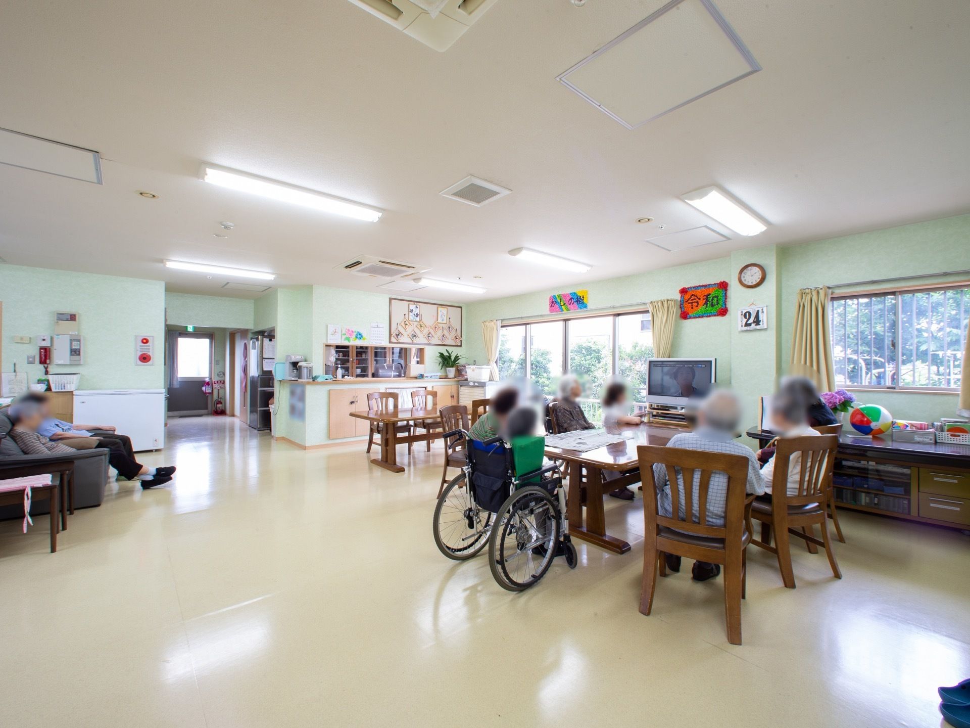 共有スペースは、テーブルセットやソファの配置の間隔を広くとっている。木製のテーブルセットは、テレビとサッシの前に置かれている。