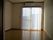 エアコンが付いたフローリングの部屋にはレースカーテンが付いた窓があり、家具などはない。