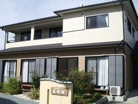 一般の住宅のような2階建ての建物。敷地内には植物がたくさん植えられ、門には住宅名が書かれ、日当たりもよい。