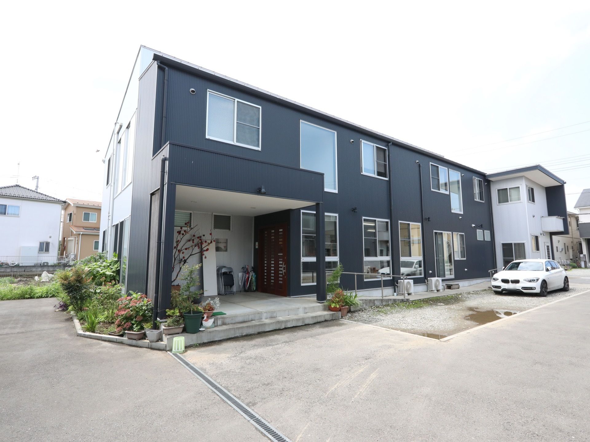 木造2階建ての清楚な佇まいの建物である。外壁は濃いブルーで塗られている。左端に玄関があり、スロープのある通路が設けられている。