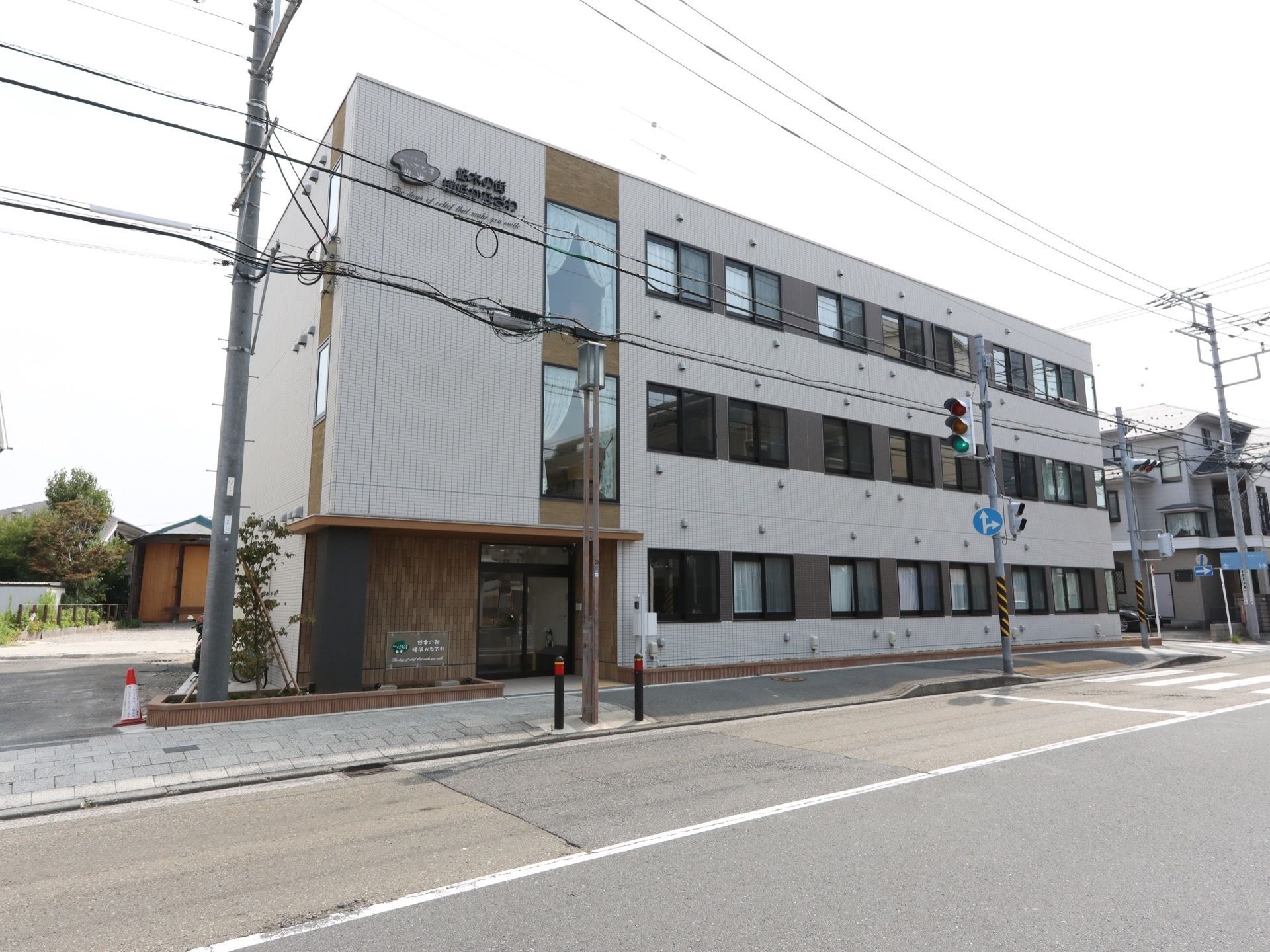 オフホワイトを基調とした３階建ての建物。周辺には木が植えられている。