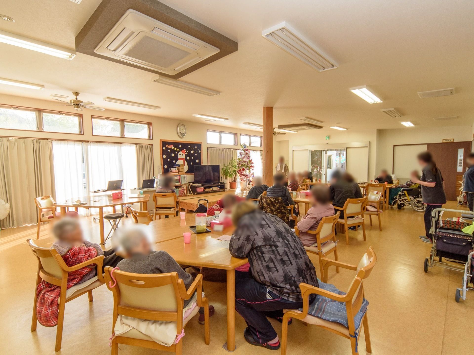 広々と明るいリビングにはテーブルがいくつも置かれ、たくさんの入居者様が集まっている。通路が広く確保され、歩行器や車椅子でも通行しやすい。