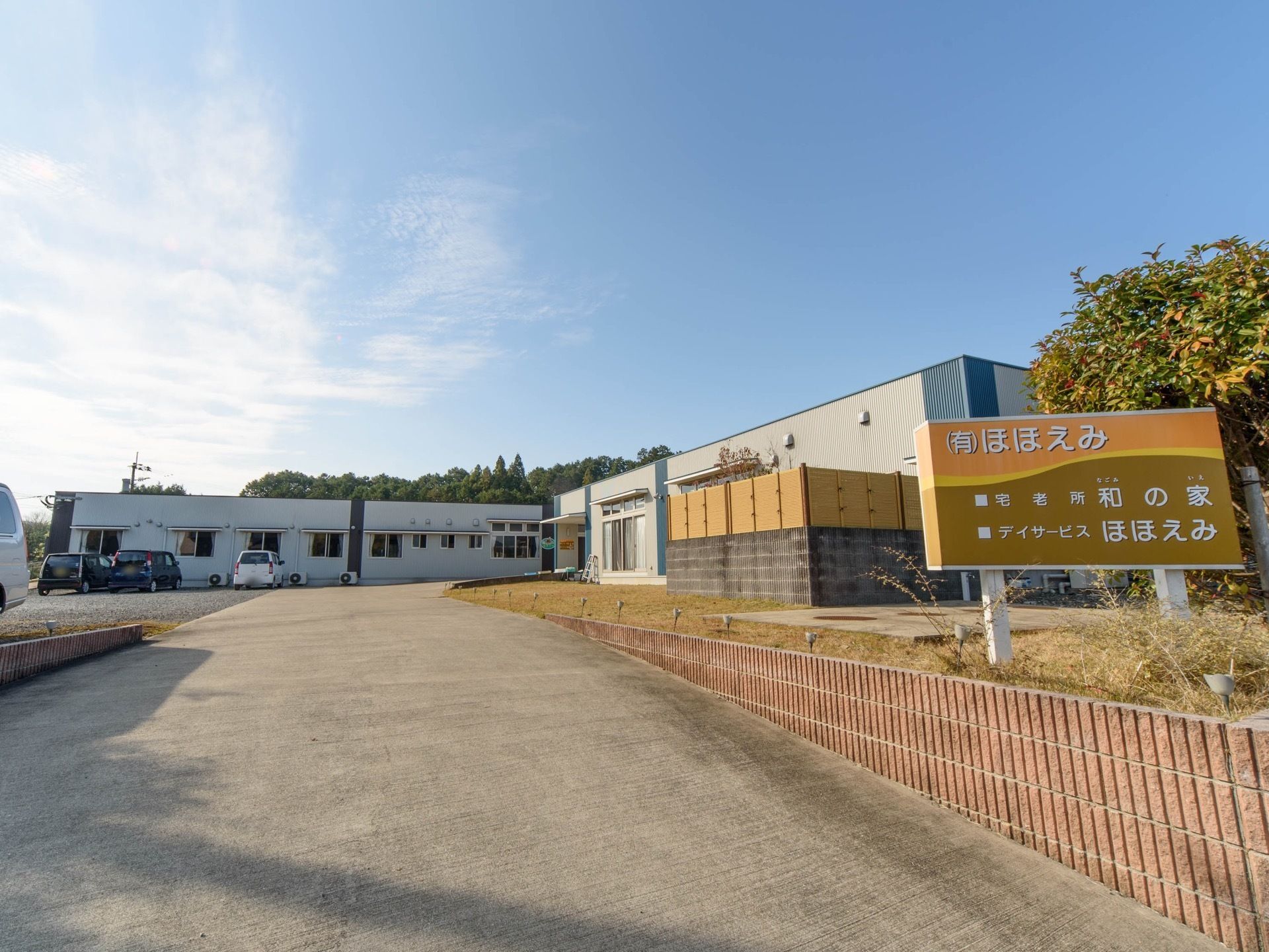 広々とした敷地の中に、Ｌ字型の平屋の建物がゆったり建っている。一部を芝生敷きにして、樹木などを植えている。