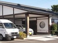 三角屋根が付いた平屋建ての建物は白壁で和の雰囲気。建物の前には駐車場がある。