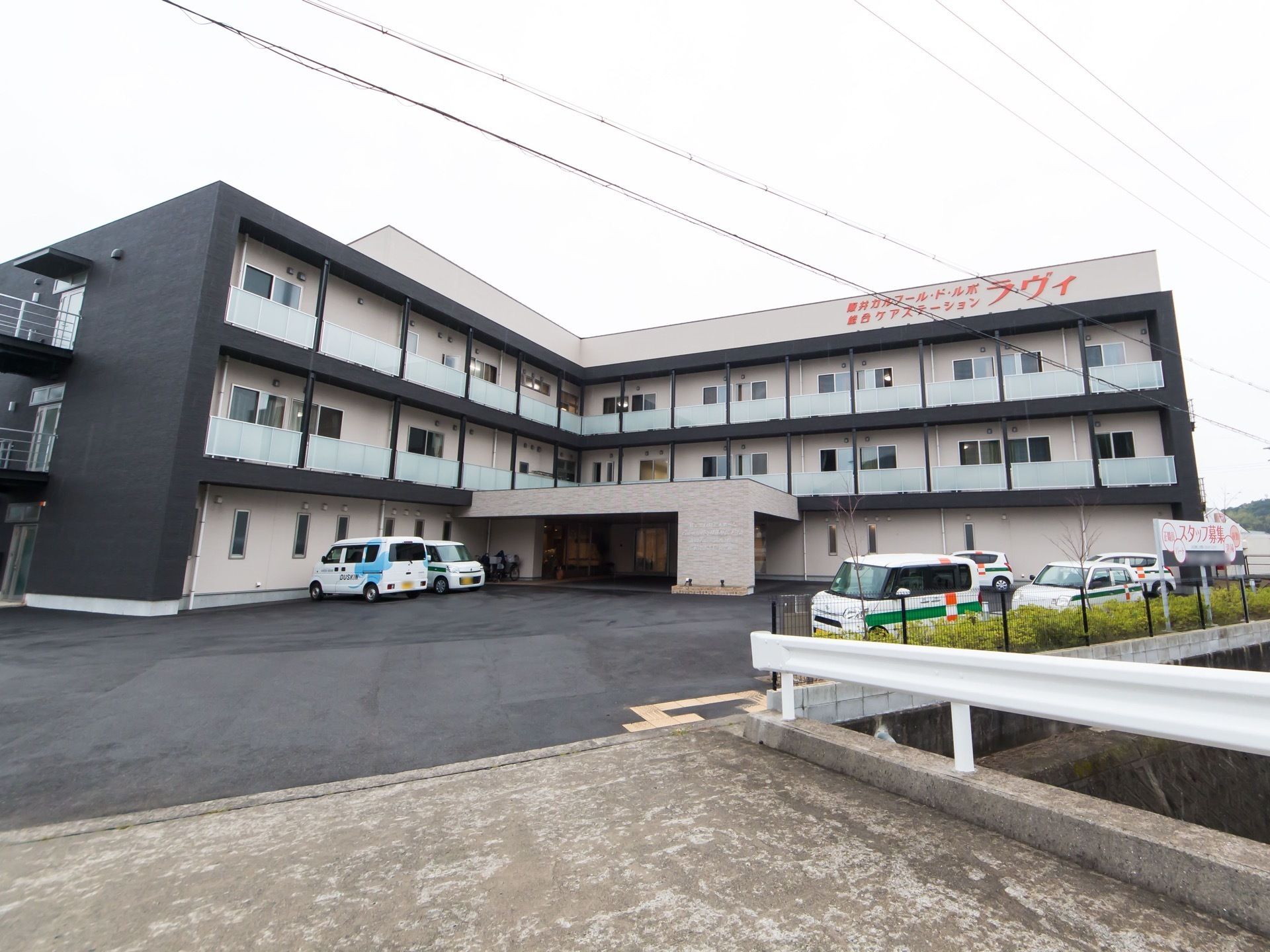 敷地の前に用水路に係る小さな橋がある。くの字型の構造をした３階建ての施設である。玄関に車寄せがある。