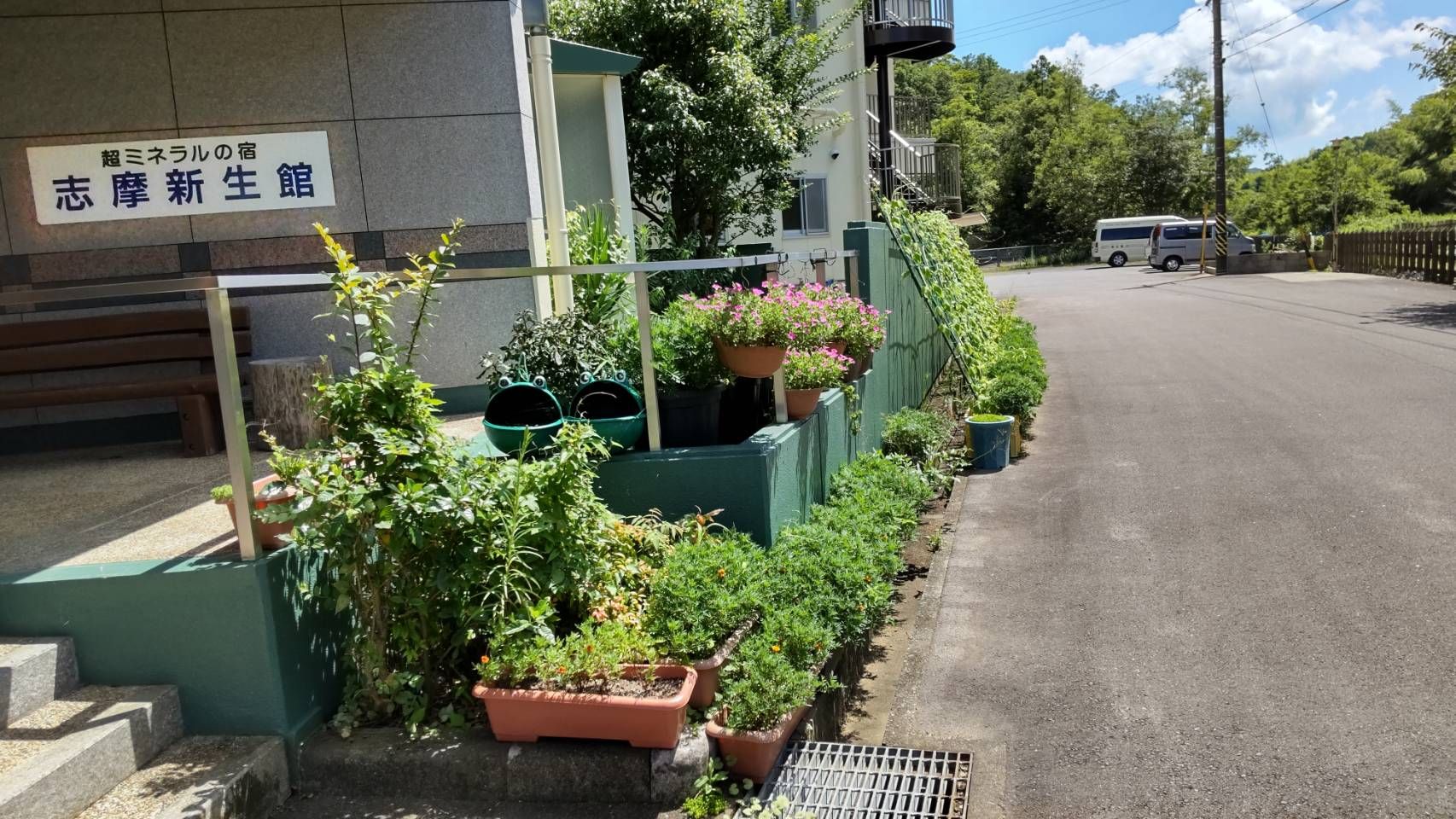 志摩新生館の看板とお出迎えの人形がある、4階建ての建物
