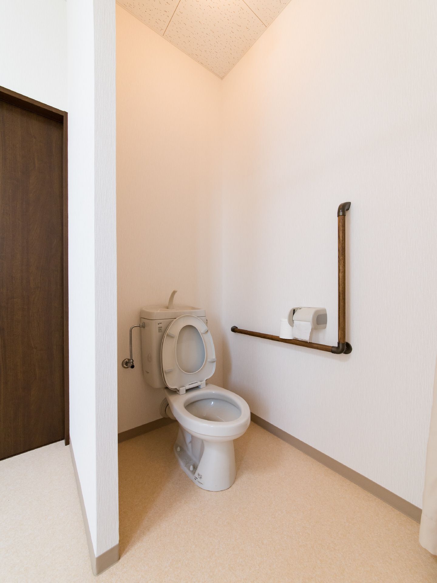 居室内に設けられている白い壁とベージュの床が明るい雰囲気のトイレ。扉がないタイプのトイレは車椅子の方もストレスなく利用できる。
