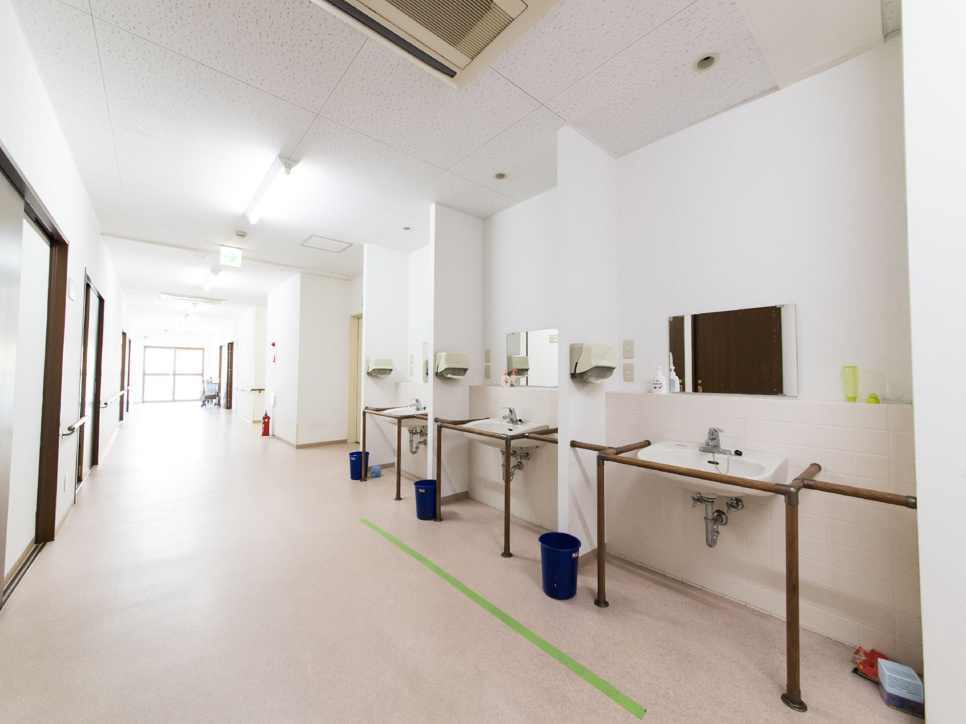 広々とした廊下の中央辺りに設置されている鏡が飾られている3台の洗面台。周りを手すりで囲んであるので、安定感がある。