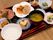 ８種類のおかずなどの小鉢や皿と、汁物やご飯の盛られた碗がお盆に載せられている。お盆には箸も一膳添えられている。